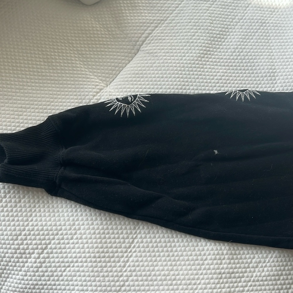 Black sweater with white sunny’s on the middle top and down the sleeves